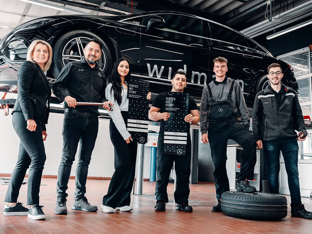 Unsere Servicemitarbeiter vor einem Mercedes-Benz EQE auf einer Hebebühne.