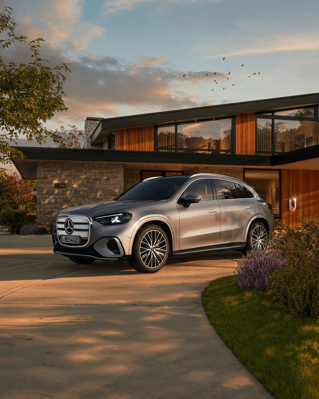 Silberner Mercedes-SUV vor modernem Haus im Abendlicht.