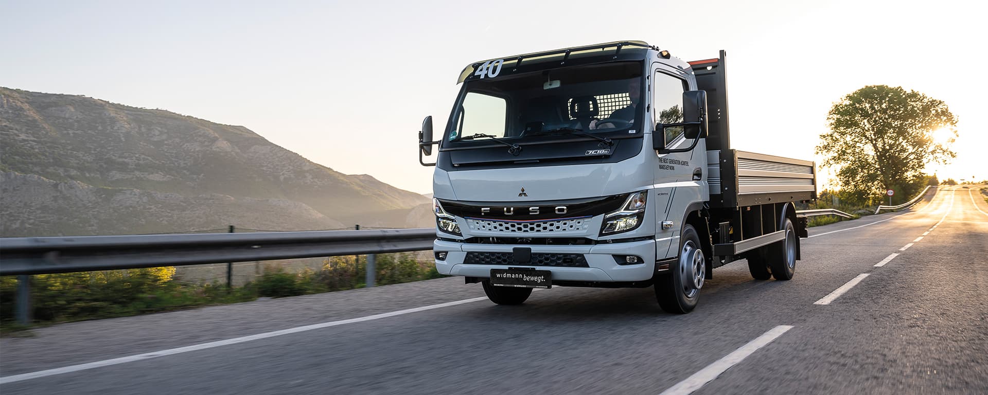 Ein weißer Fuso eCanter fährt auf einer Straße.