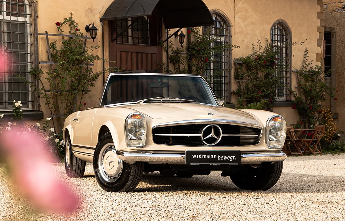 Ein beiger Mercedes-Benz Oldtimer vor einem Hauseingang.
