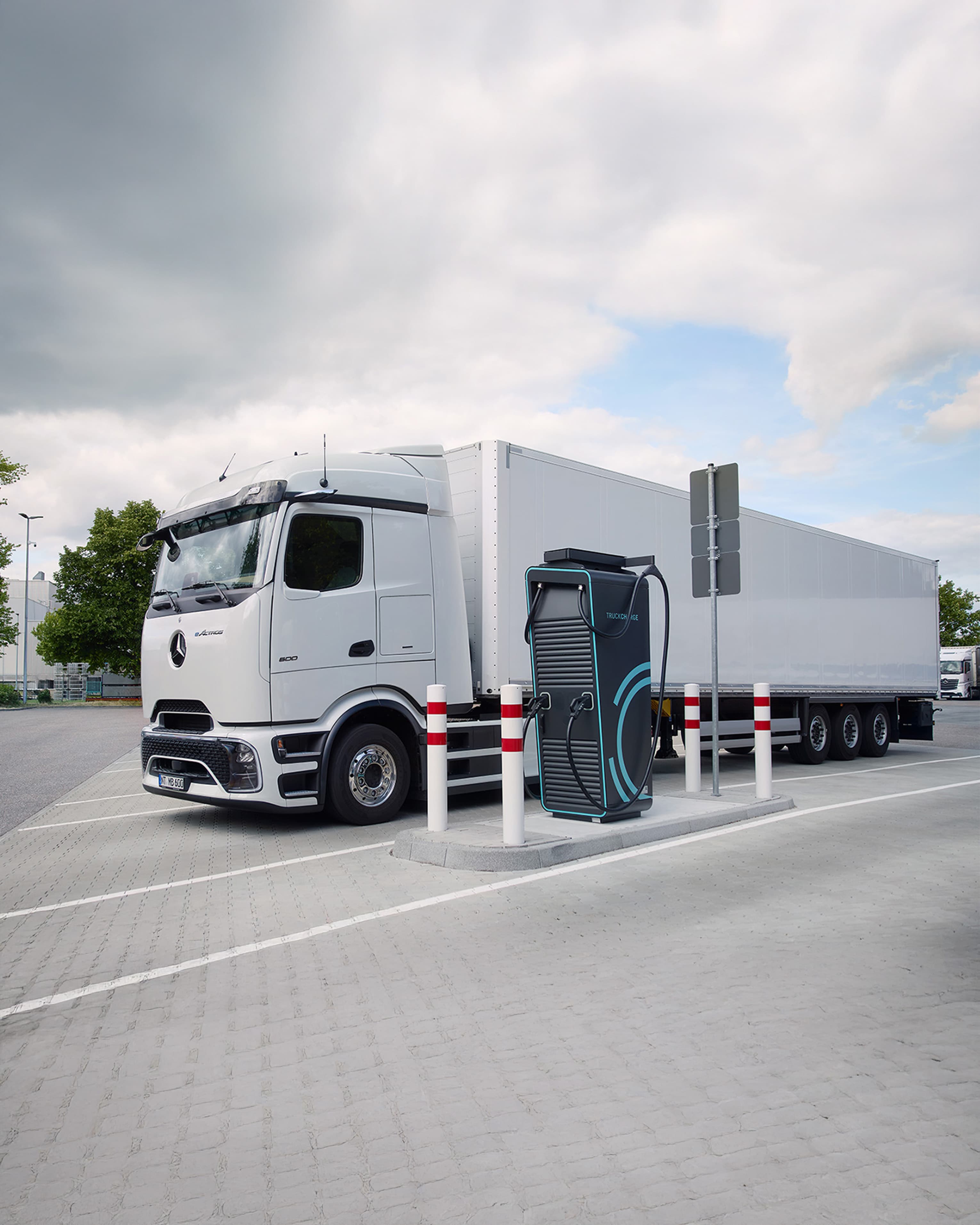Elektrischer Sattelzug beim Laden an einer Schnellladestation auf einem modernen Ladepark für Nutzfahrzeuge.