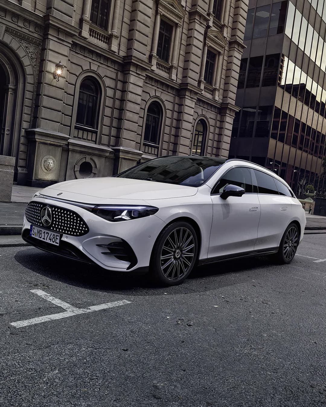 Ein weißer CLA Shooting Brake steht vor einem hohen Gebäude in der Stadt