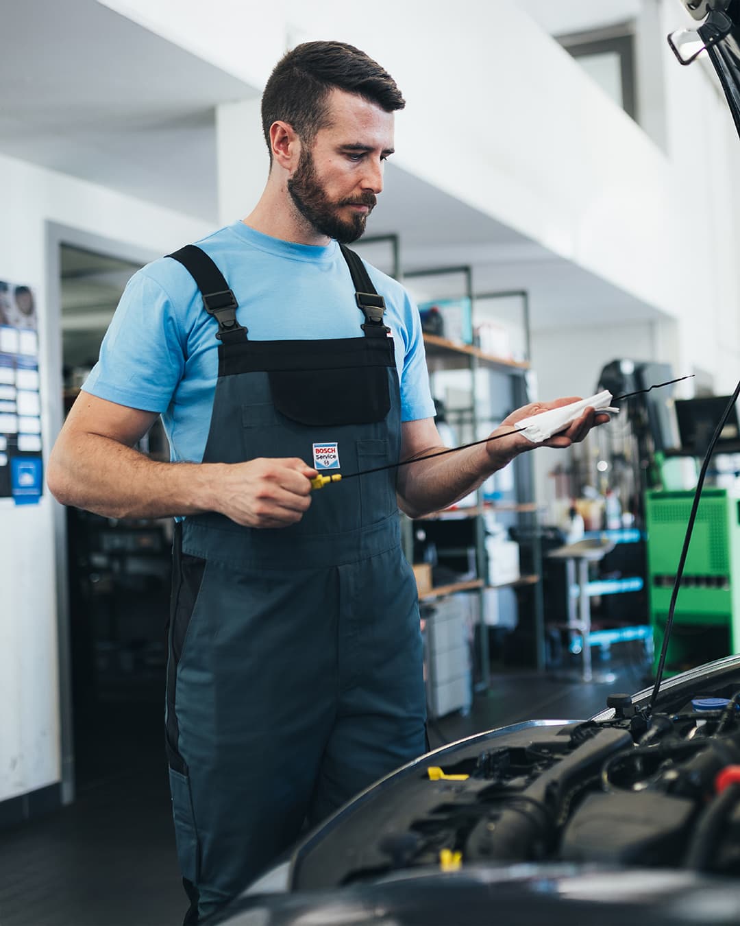Ein Bosch Mechaniker an einer geöffneten Motorhaube mit einem Ölprüfstab.