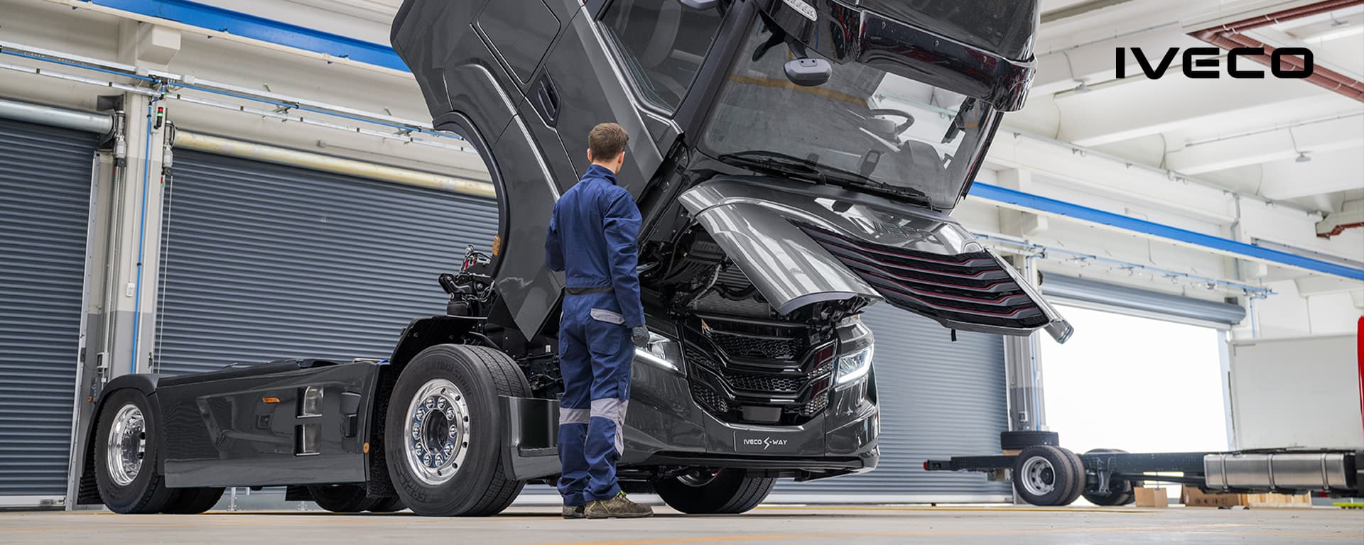 Ein Werkstattmitarbeiter vor einem IVECO Lkw mit geöffneter Motorhaube.