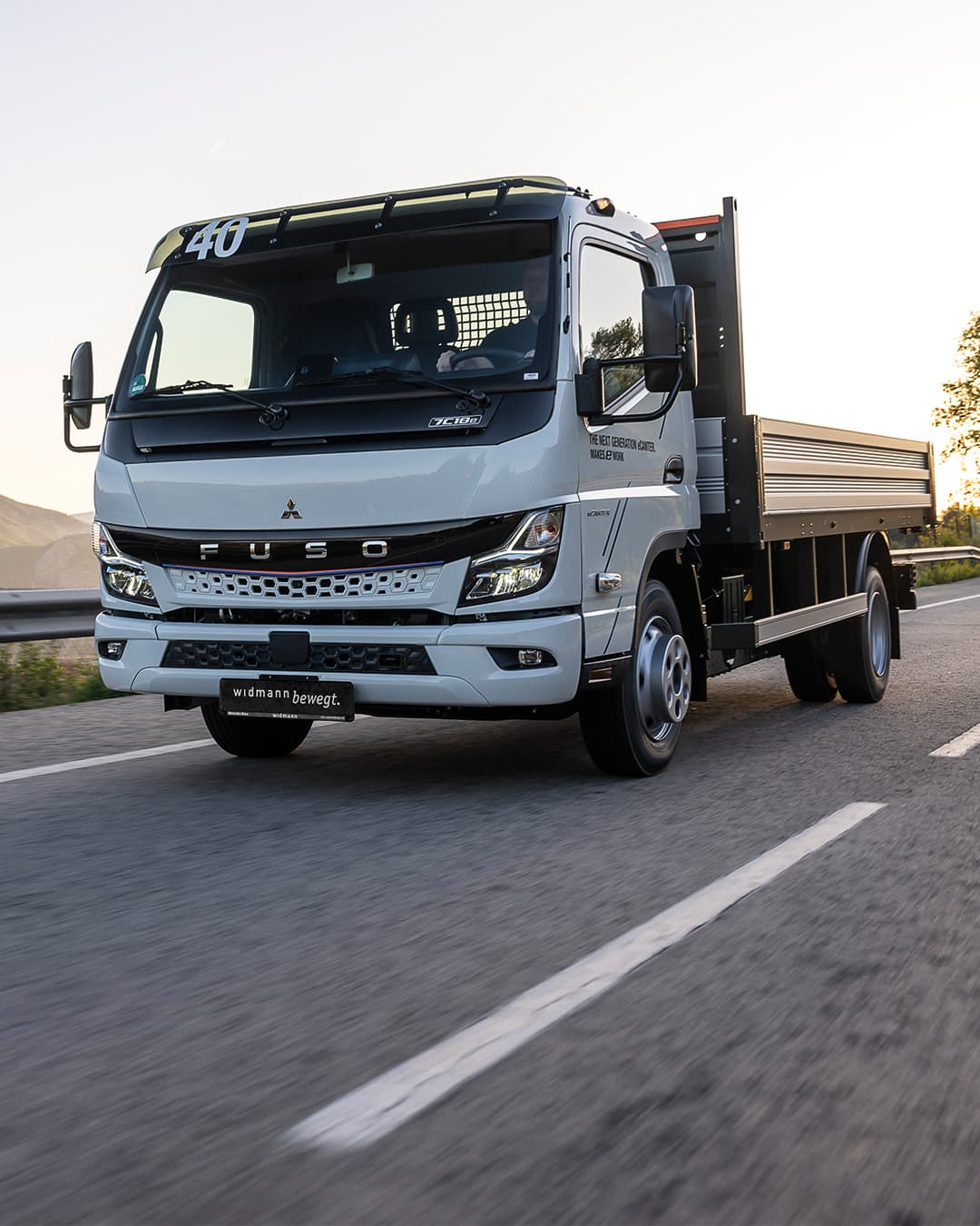 Ein weißer Fuso eCanter fährt auf einer Straße.