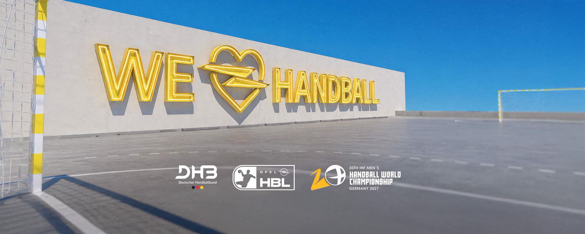 Handballfeld mit „WE LOVE HANDBALL“-Schriftzug sowie den Logos von DHB, HBL und der Handball-Weltmeisterschaft.
