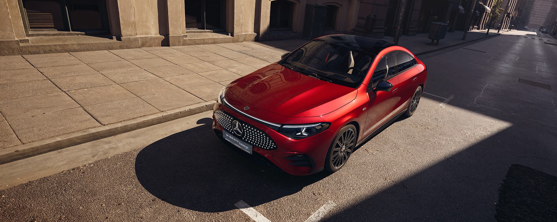 Ein roter CLA steht schräg auf einer ruhigen Stadtstraße neben einem Gebäude bei Tageslicht.