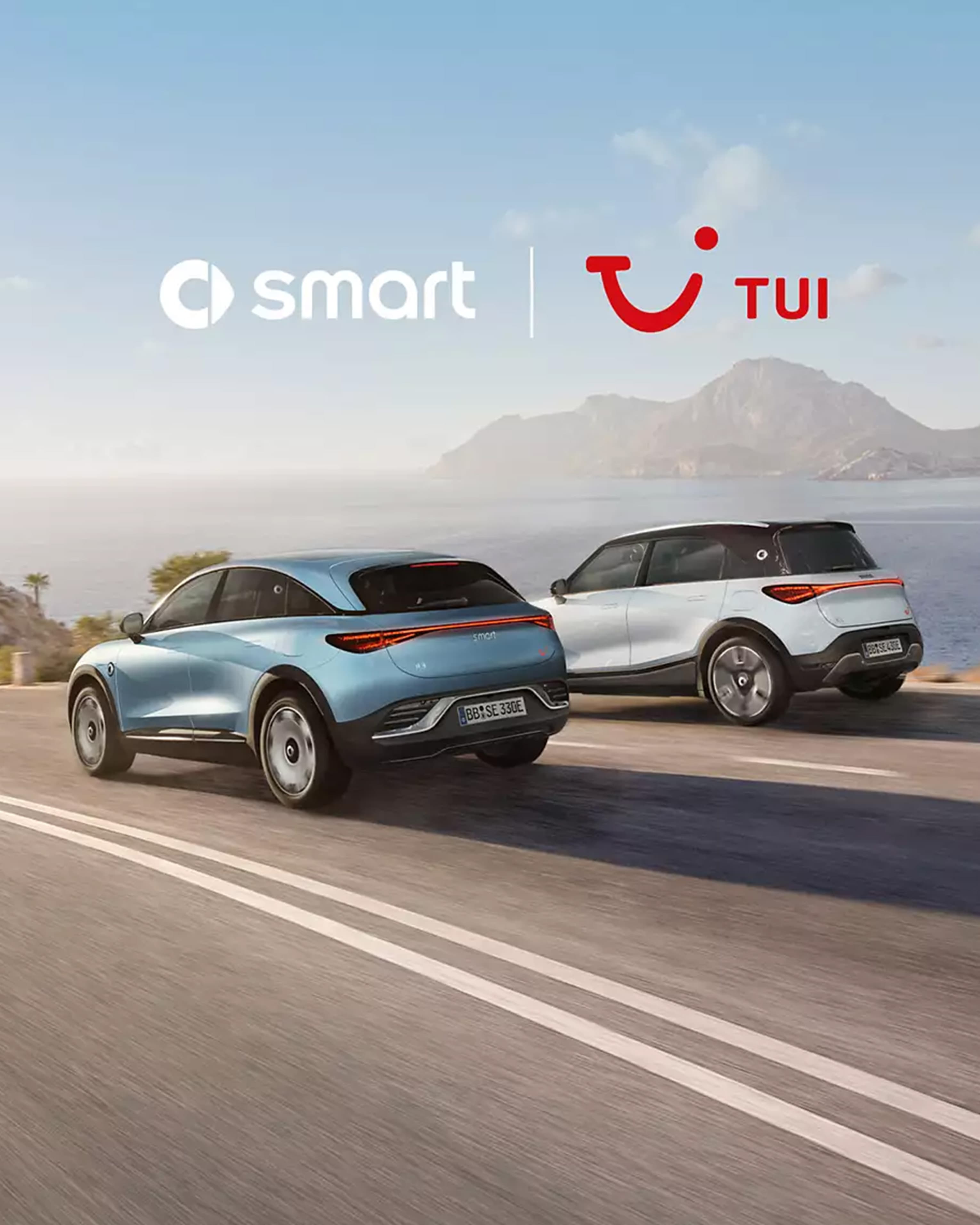 Zwei smart-Fahrzeuge fahren auf einer Küstenstraße, mit dem Meer im Hintergrund.