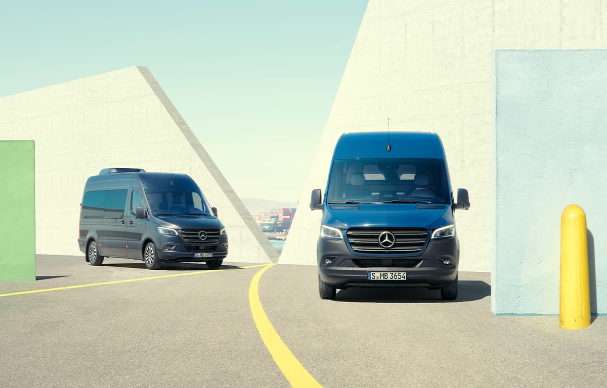 Zwei Mercedes-Benz Sprinter auf einem Hafengelände.