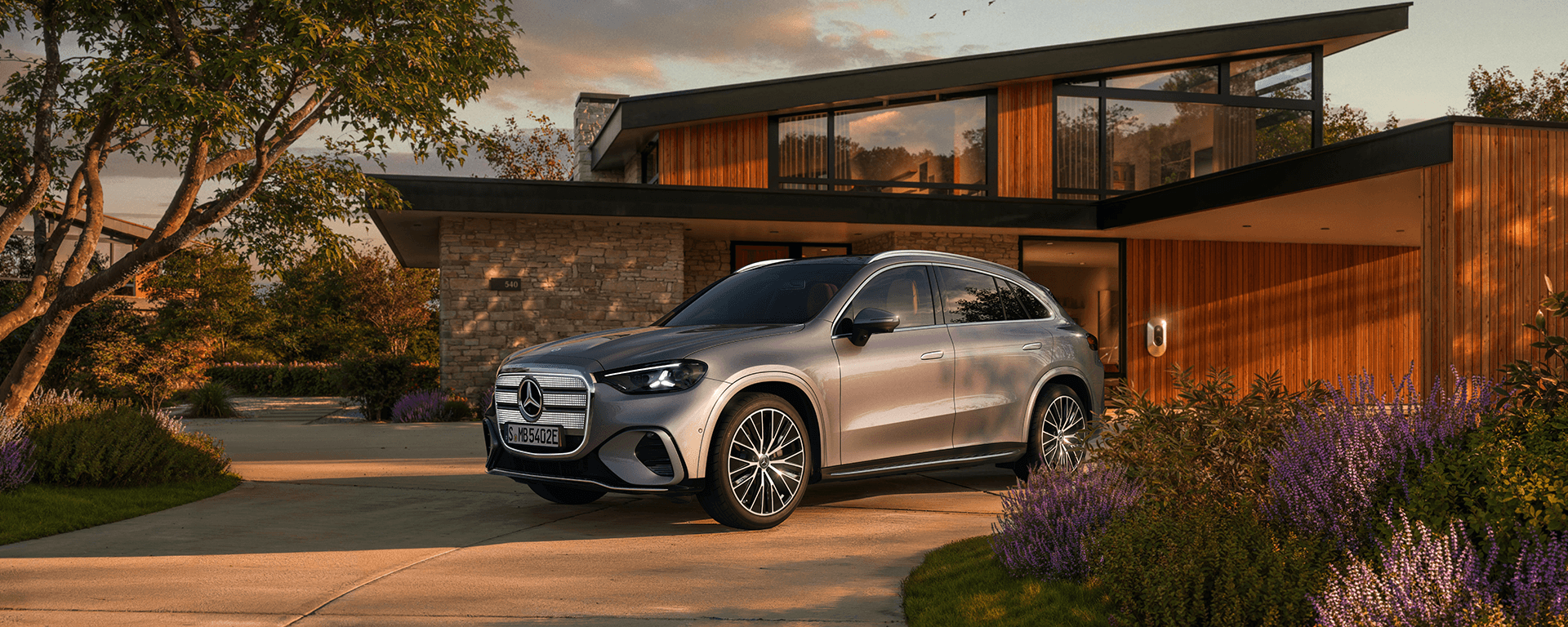 Silberner Mercedes-SUV vor modernem Haus im Abendlicht.