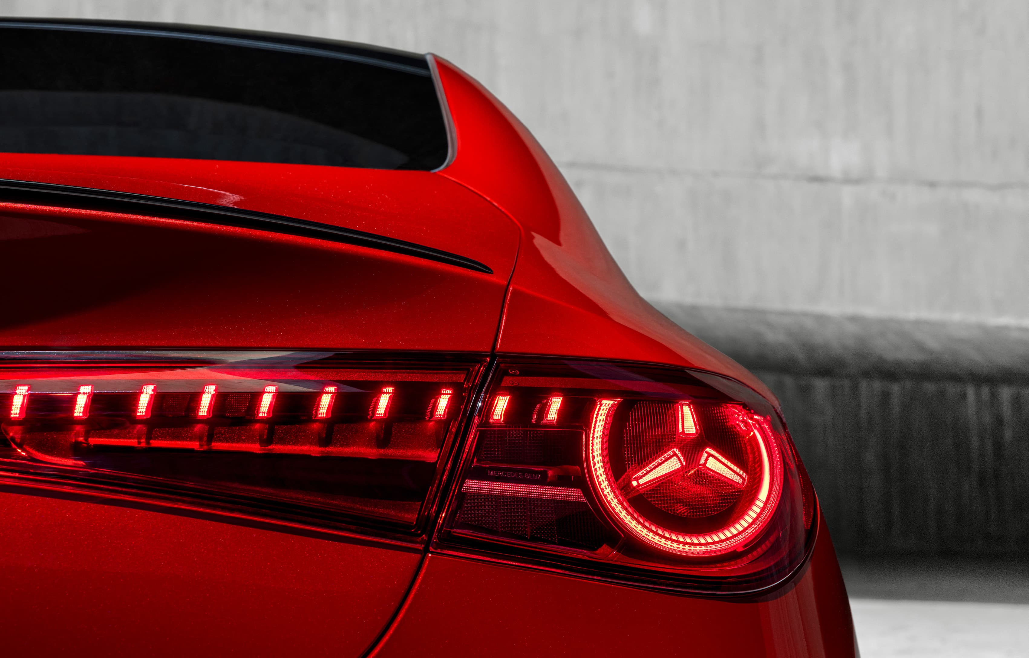 Detailaufnahme des Hecks eines roten Mercedes-Benz CLA mit beleuchtetem Rücklicht.
