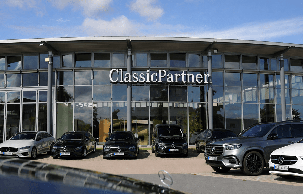 Moderne Autohausfassade mit ClassicPartner Schriftzug und mehreren Mercedes-Benz Fahrzeugen davor.