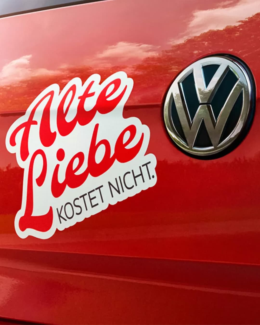 Rotes Auto mit VW-Logo und Aufkleber „Alte Liebe kostet nicht.“