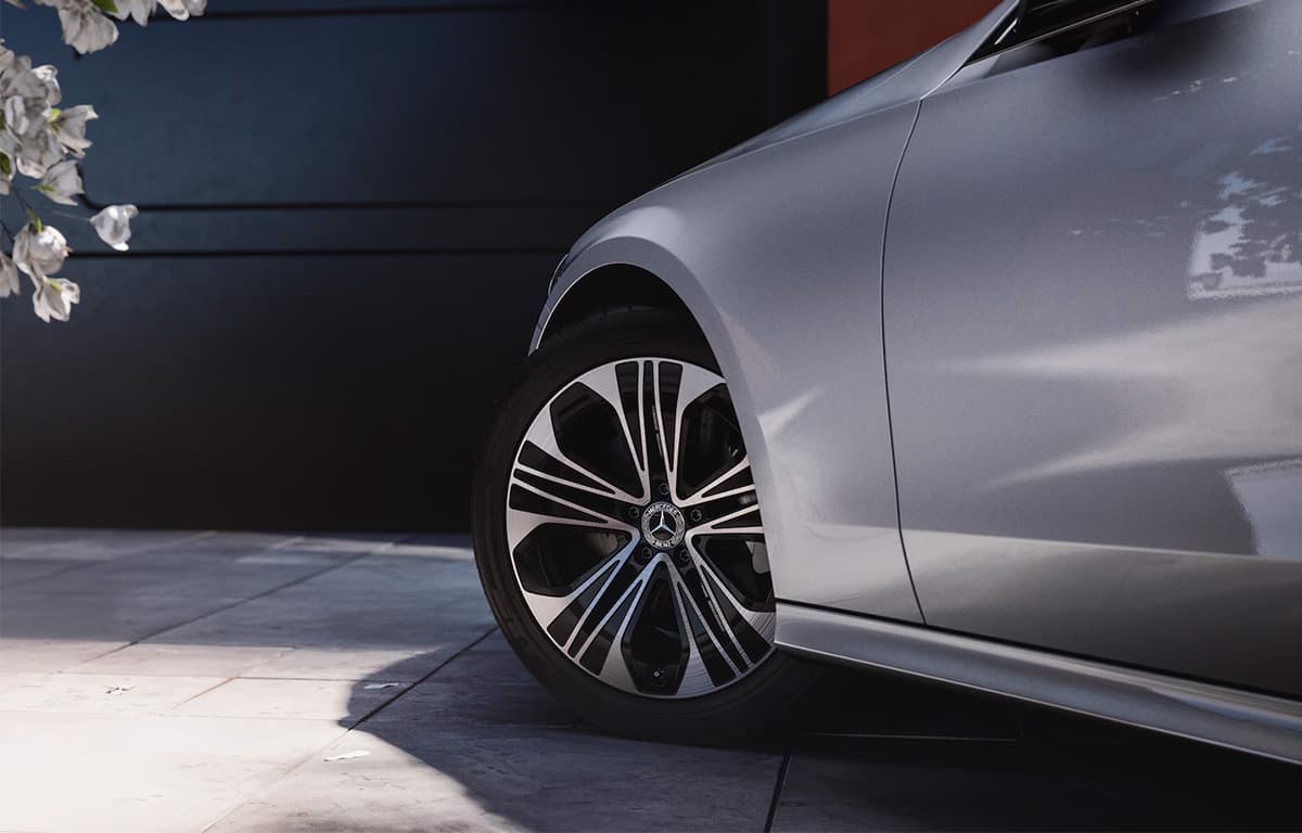 Detailaufnahme des Vorderrads und der Seitenpartie eines silbernen Mercedes-Benz Fahrzeugs.