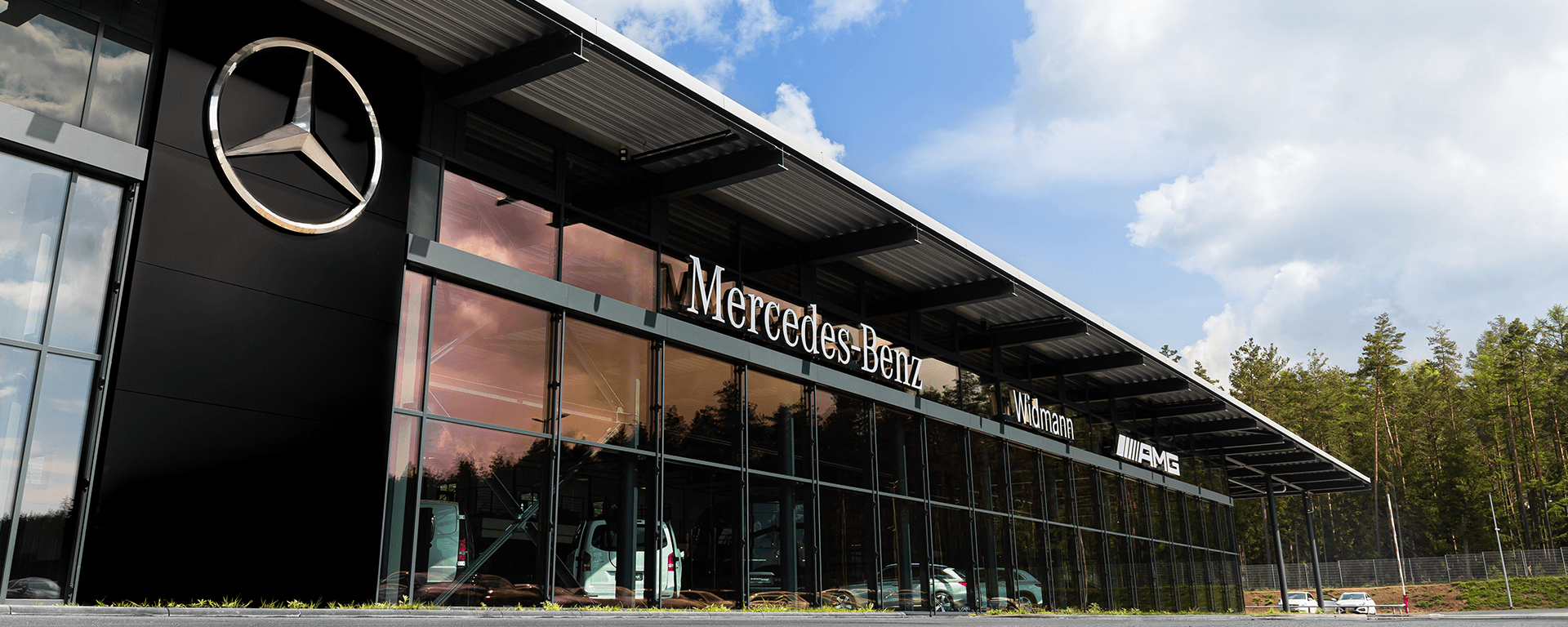 Modernes Mercedes-Benz Autohaus mit großer Glasfassade und Markenlogo an der Außenwand.