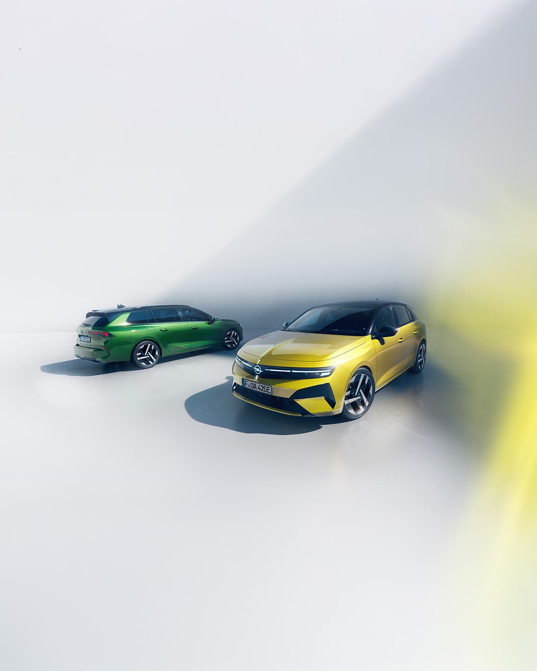 Gelber Opel Astra und grüner Opel Astra Sports Tourer in moderner Studio-Umgebung.