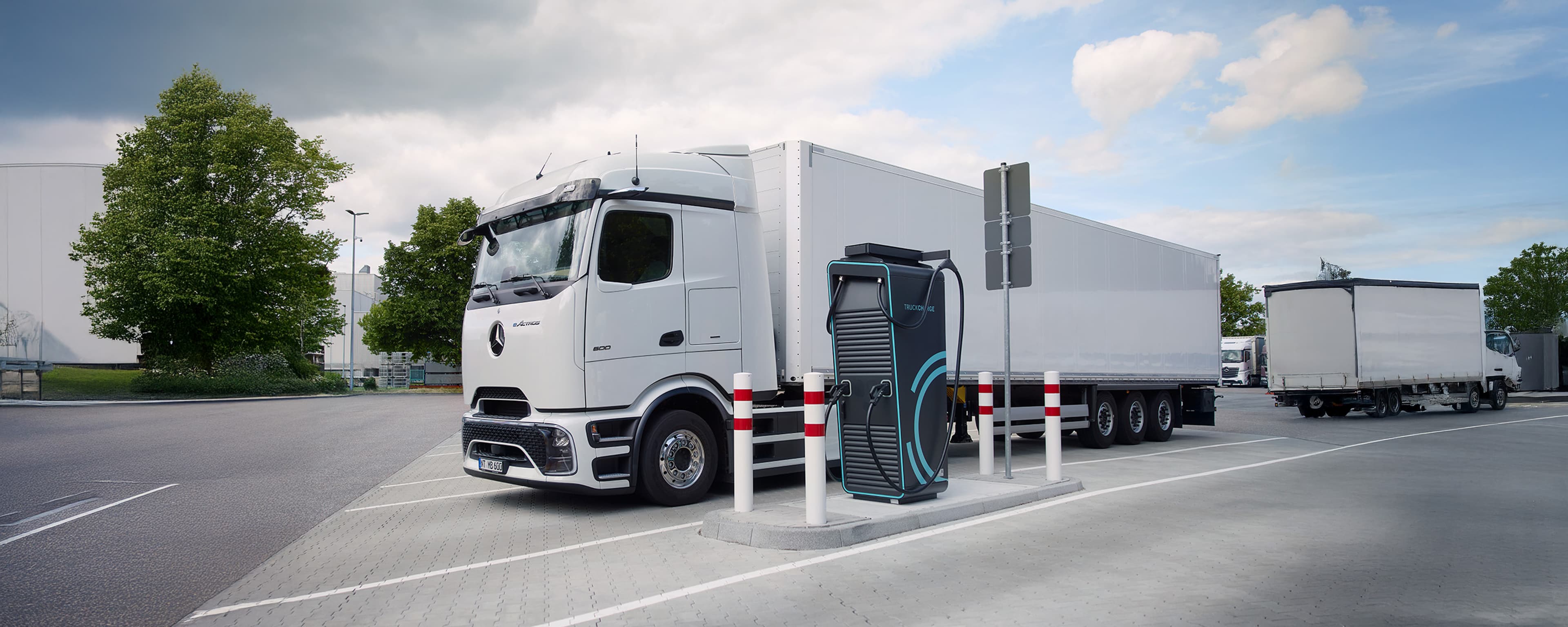 Elektrischer Sattelzug beim Laden an einer Schnellladestation auf einem modernen Ladepark für Nutzfahrzeuge.