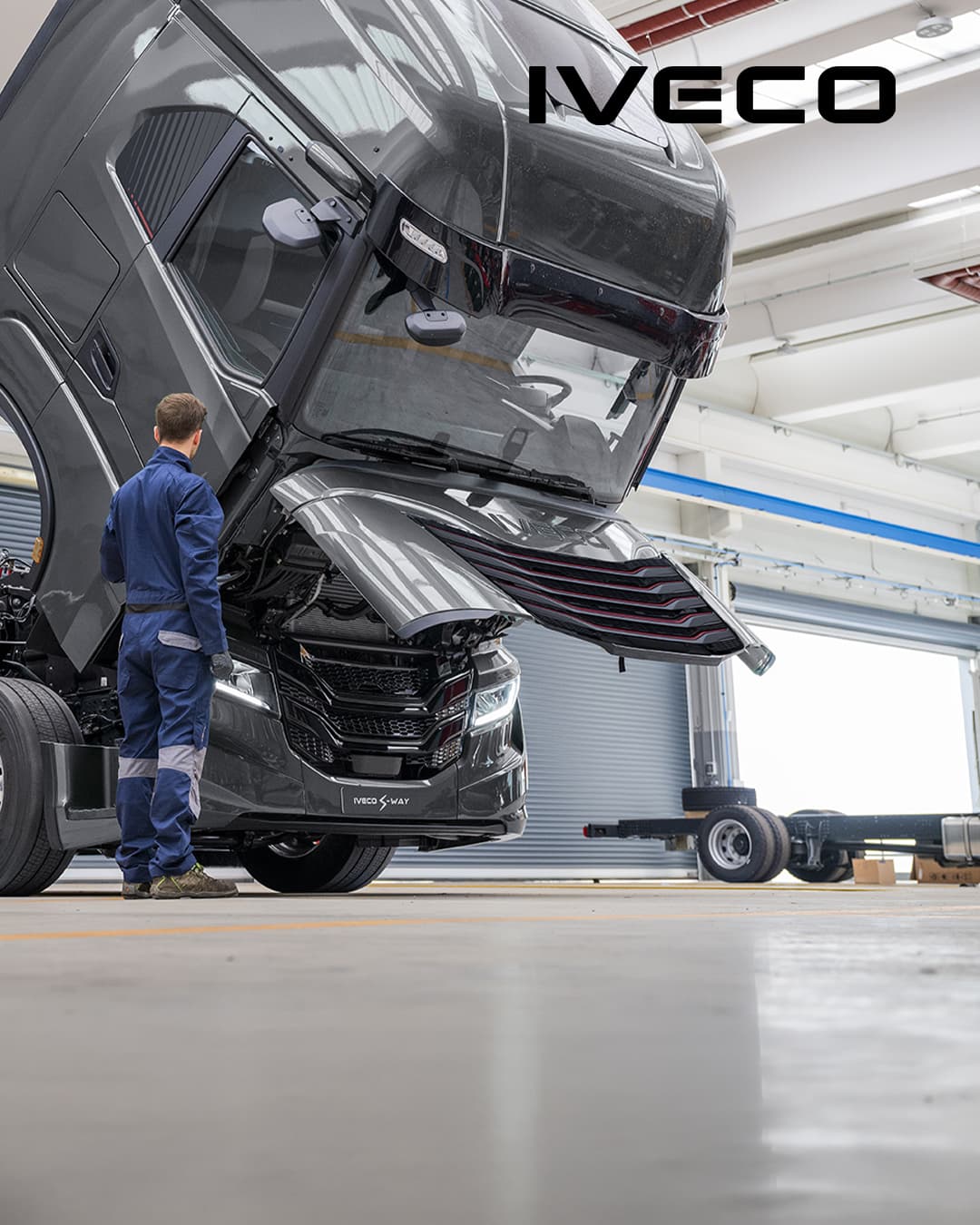Ein Werkstattmitarbeiter vor einem IVECO Lkw mit geöffneter Motorhaube.