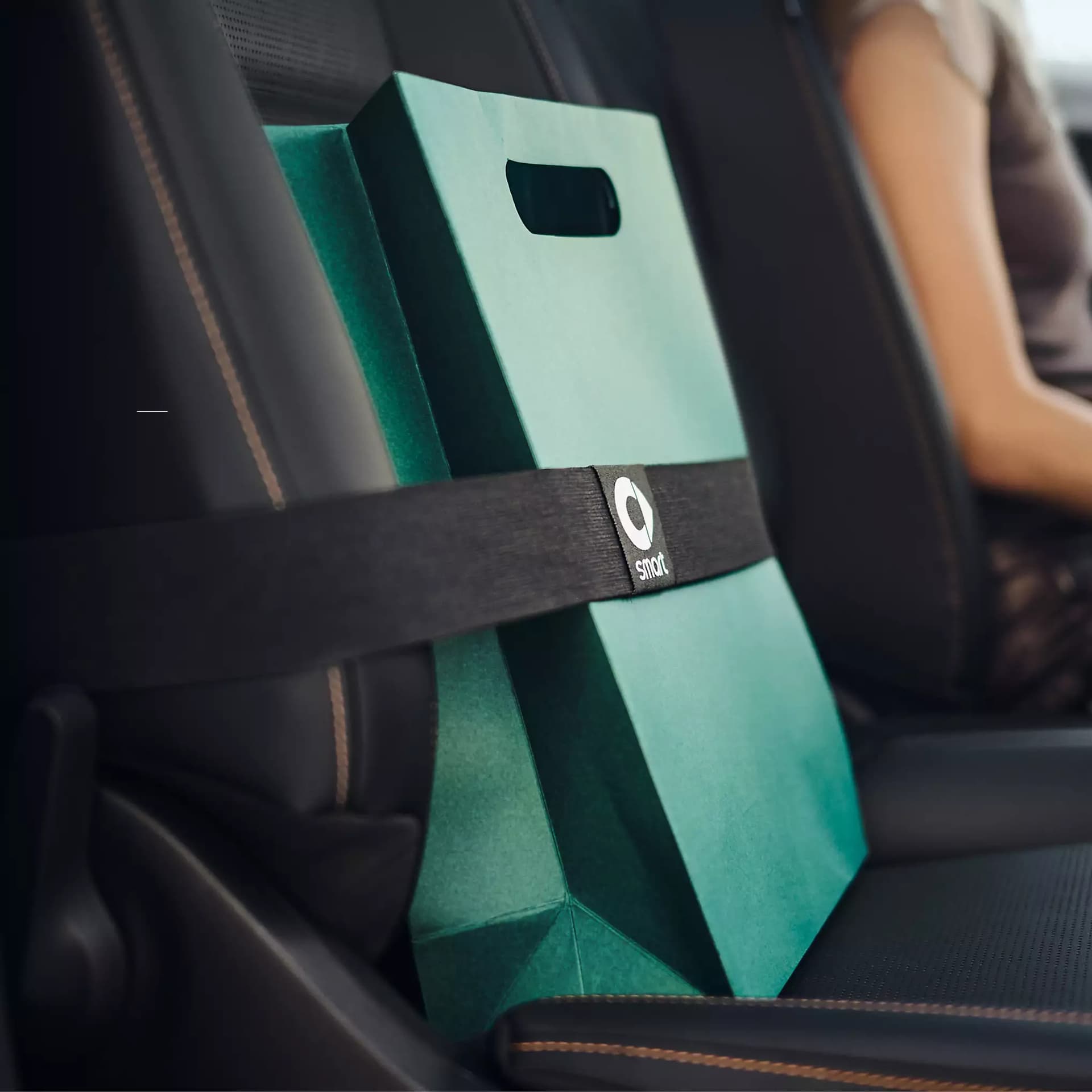 Detailaufnahme des smart Strap im smart #2, der eine grüne Tasche mit einem schwarzen Halteband auf dem Beifahrersitz sichert.